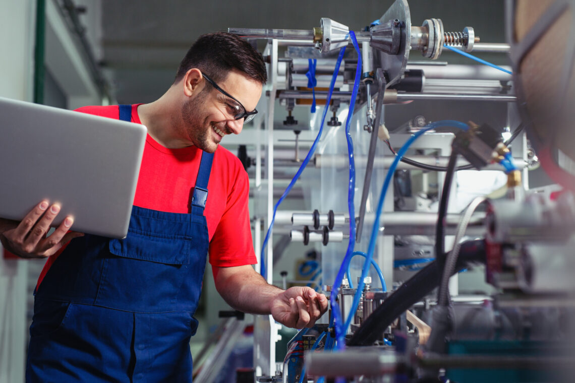 Engineer in the factory using laptop computer for maintenance.